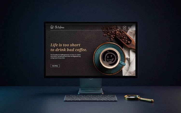 Monitor mit der Website von Kaffeewelt, davor eine Lupe